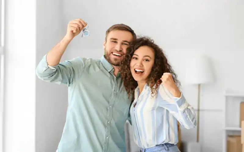 Pareja joven con las llaves de su primer piso en Córdoba Pareja feliz menor de 35 años mostrando las llaves de su primera vivienda en Córdoba tras conseguir su hipoteca