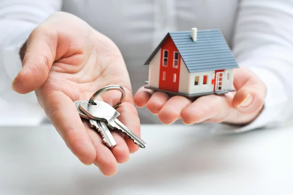 Manos sosteniendo unas llaves y una casa en miniatura para una hipoteca en Córdoba