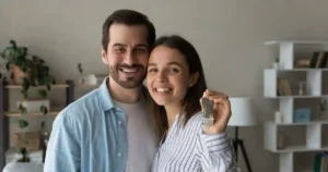 Pareja joven mostrando las llaves de su nueva casa tras conseguir una hipoteca en Córdoba
