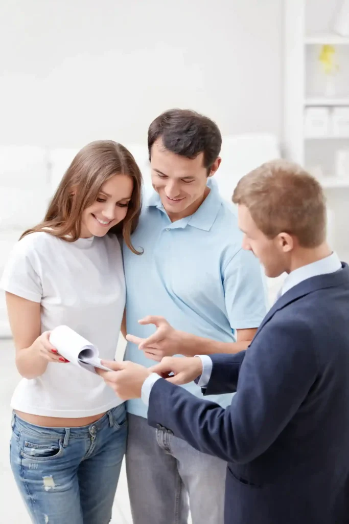 Pareja joven revisando documentación con un asesor financiero durante un proceso hipotecario