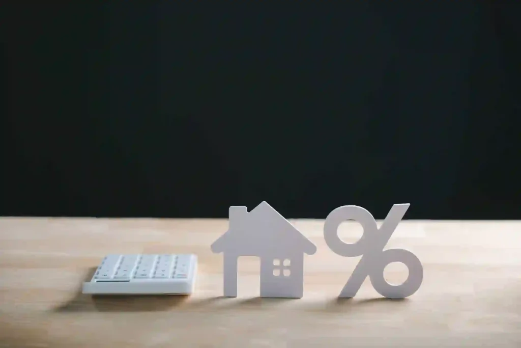 Calculadora junto a una casa y símbolo de porcentaje para calcular una hipoteca 95