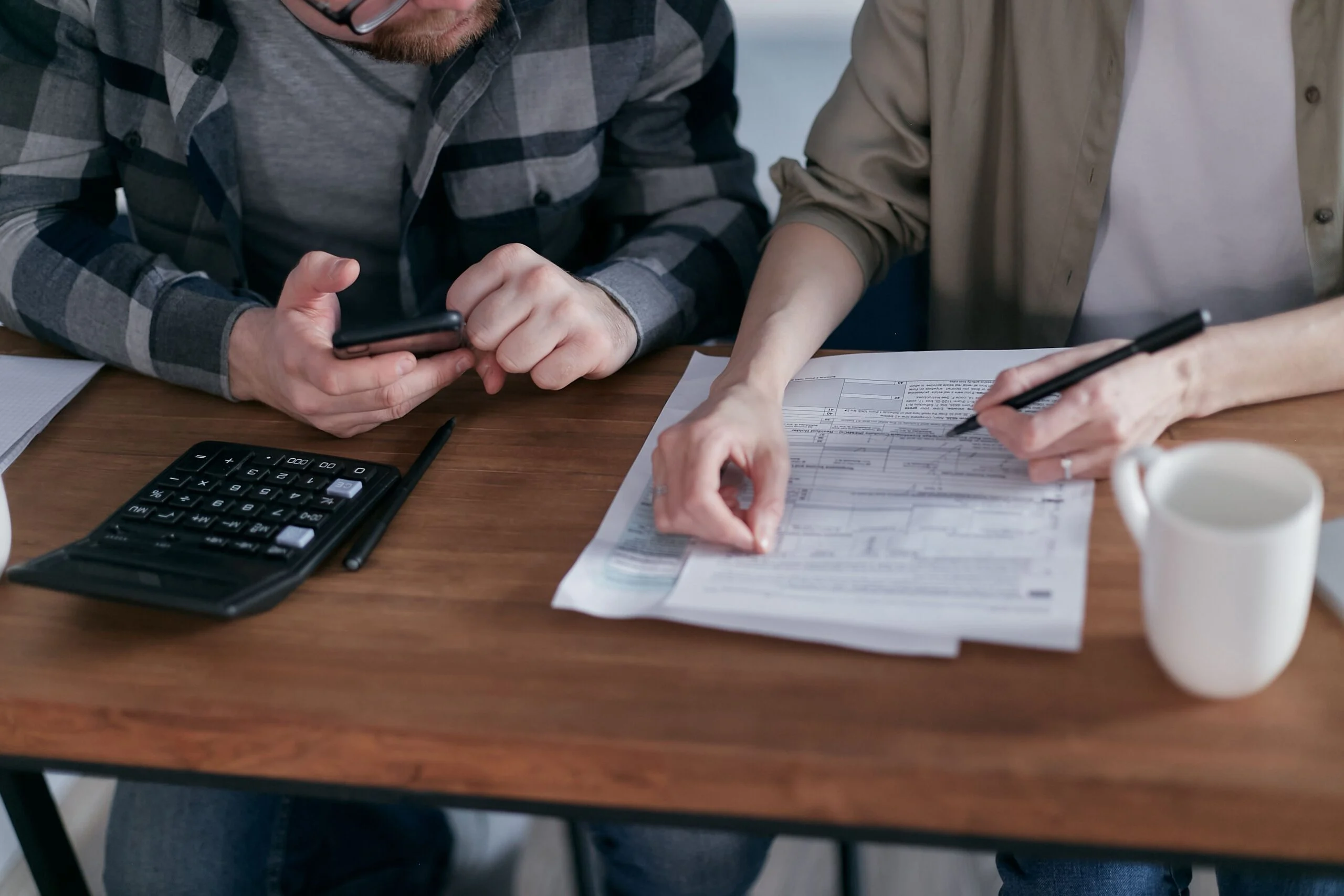 Pareja revisando sus finanzas con calculadora, documentos y ordenador