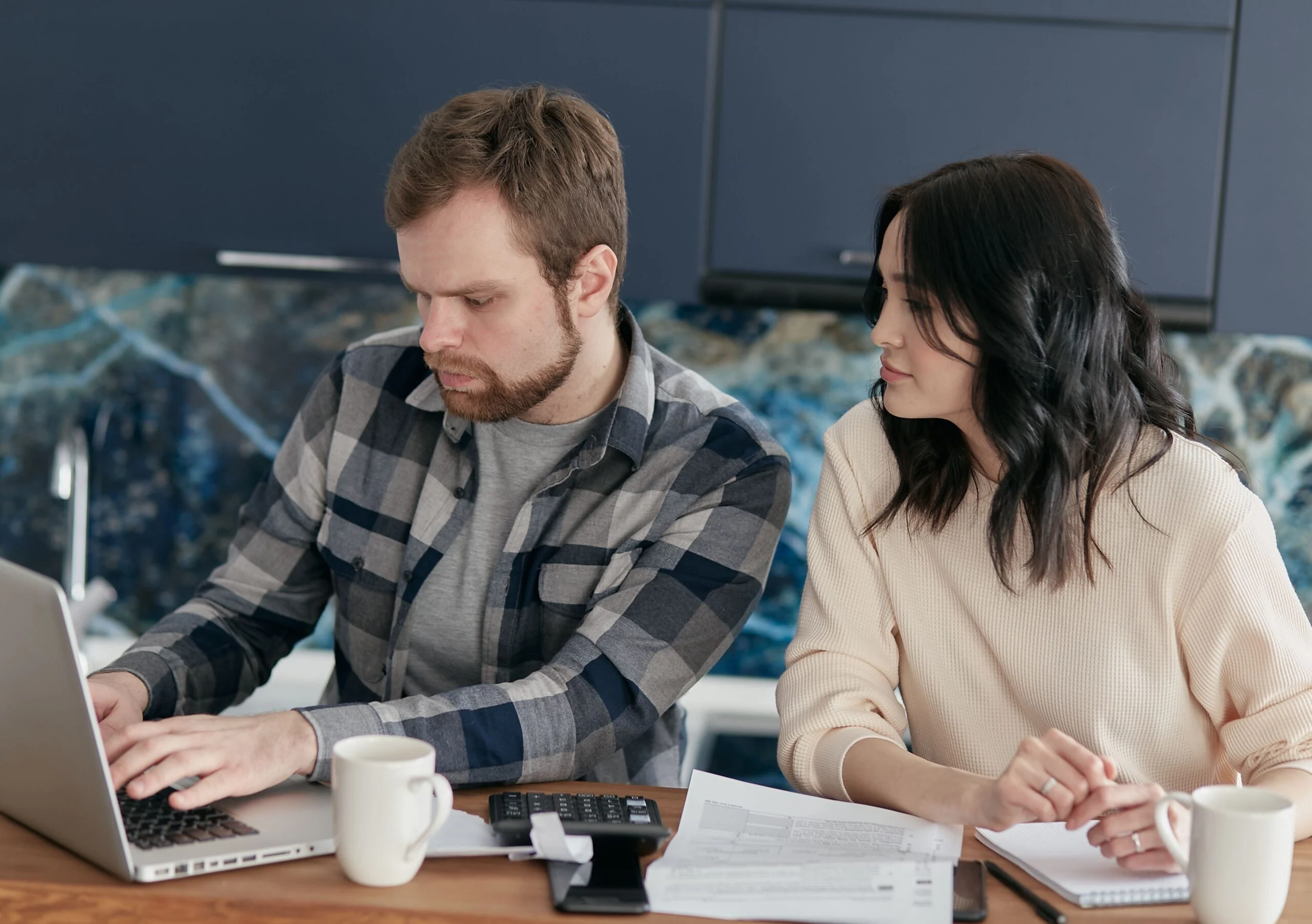 Pareja revisando documentación financiera con un ordenador portátil